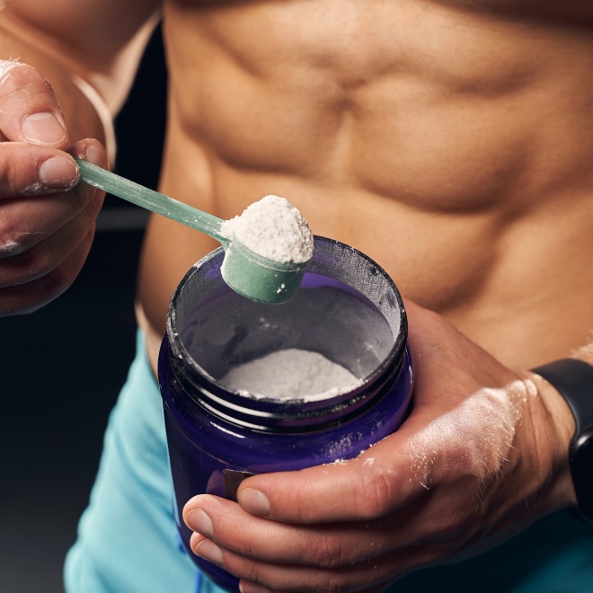 shirtless-muscly-man-wearing-sport-shorts-scooping-powder-protein-from-jar.jpg