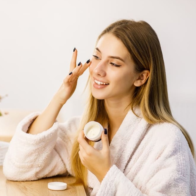 young-beautiful-blonde-girl-cares-face-skin-with-moisturizer-front-mirror-1.jpg